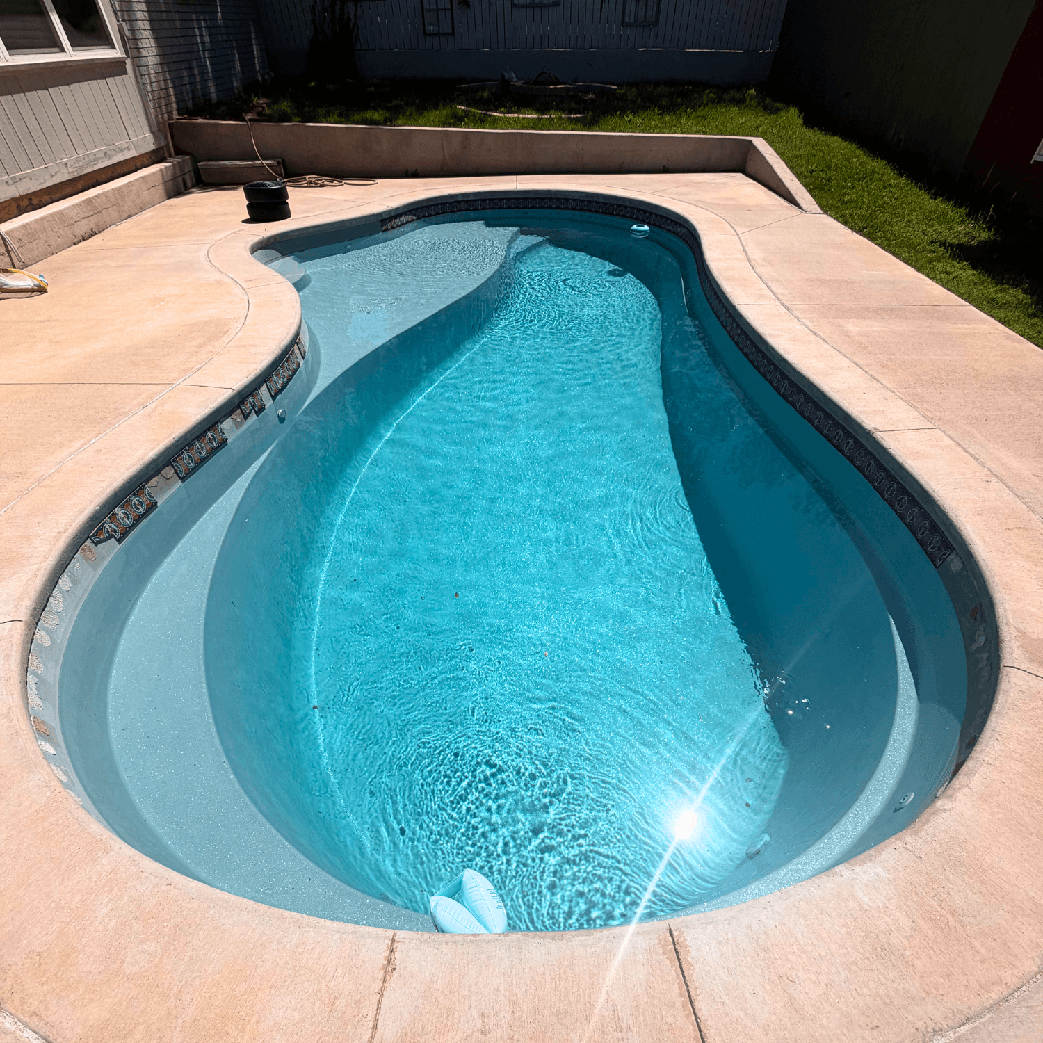 Shipwrecked Pools team member skimming and servicing a swimming pool